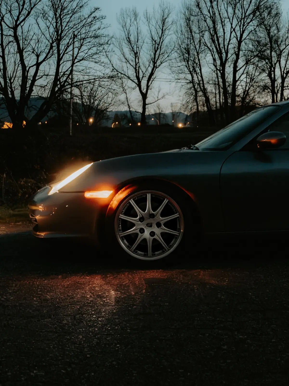 Coupé sportif au crépuscule, phares allumés
