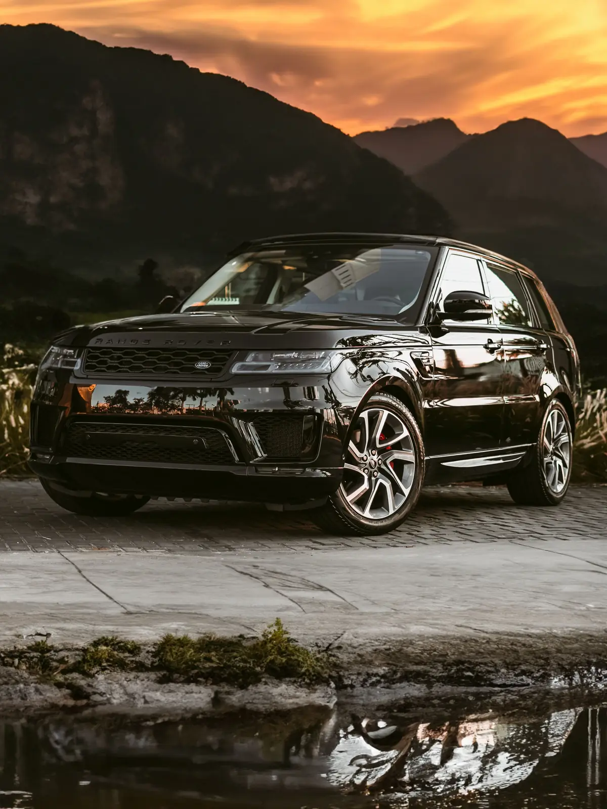 SUV noir au coucher du soleil, devant des montagnes