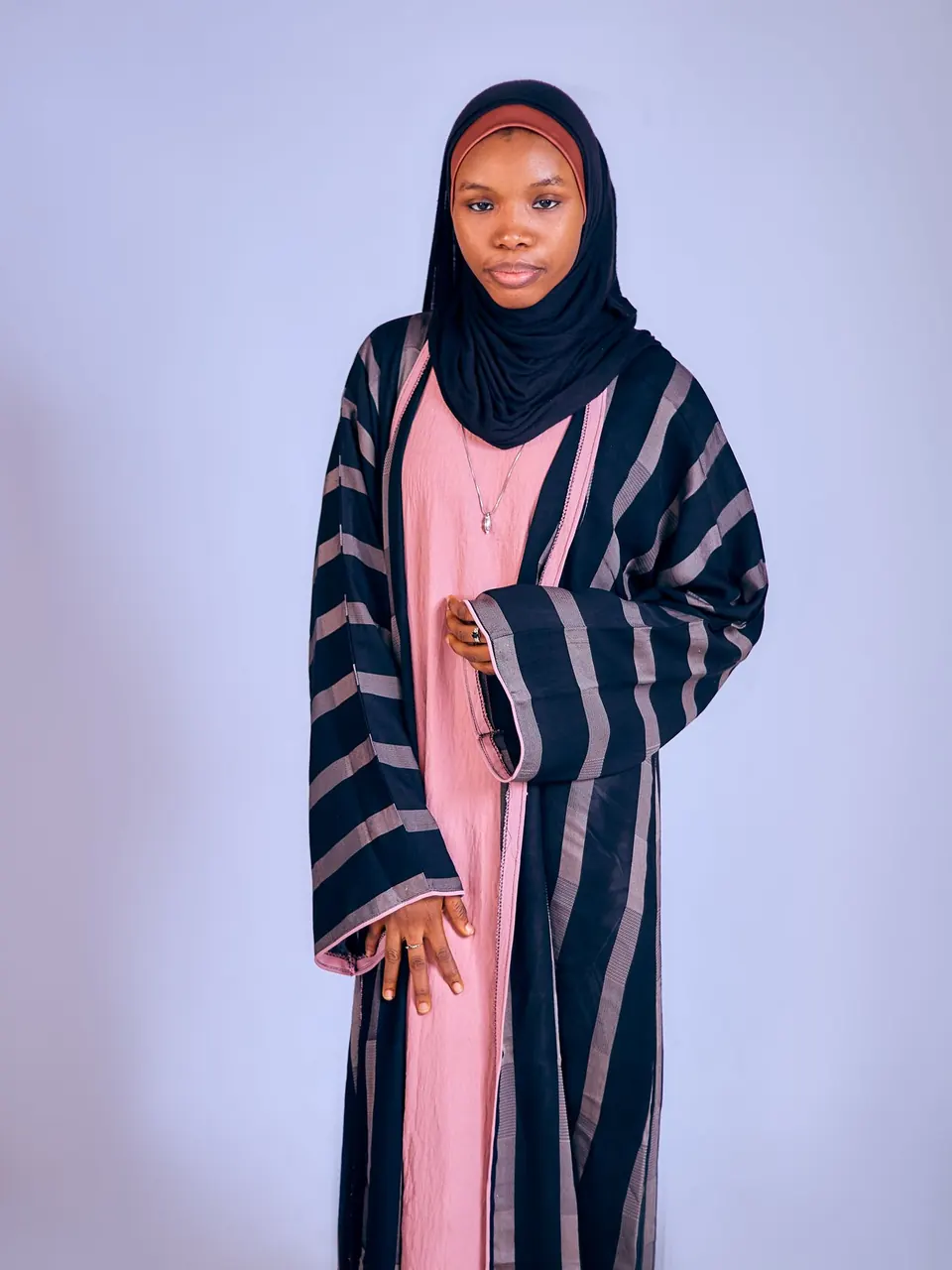 Une femme en abaya rayée bleu marine sur une robe rose