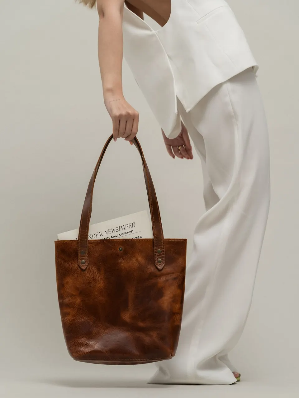 Le cabas en cuir cognac tenu à la main