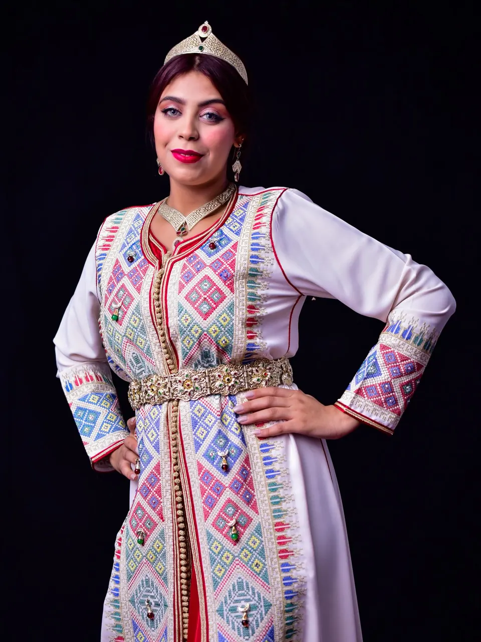Une femme en caftan ivoire brodé de motifs colorés, ceinture dorée