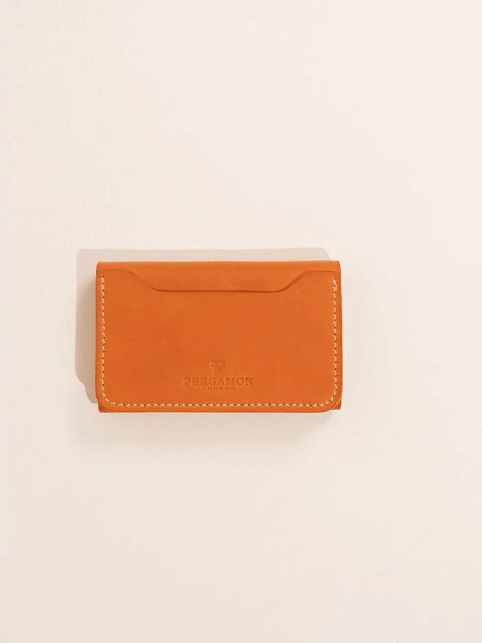 Un porte-cartes en cuir naturel sur fond beige